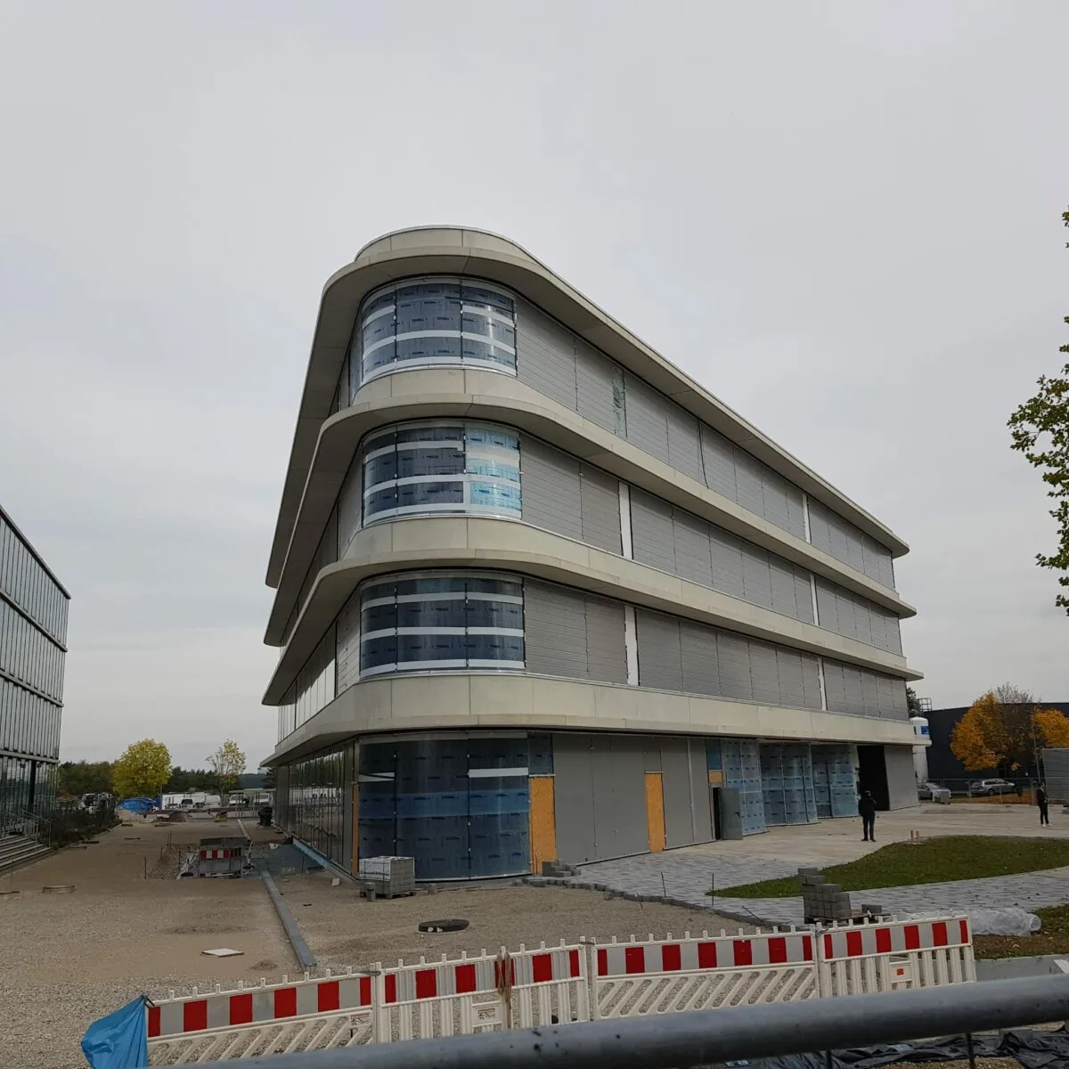 Modern laboratory building under construction with a curved design and large windows.
